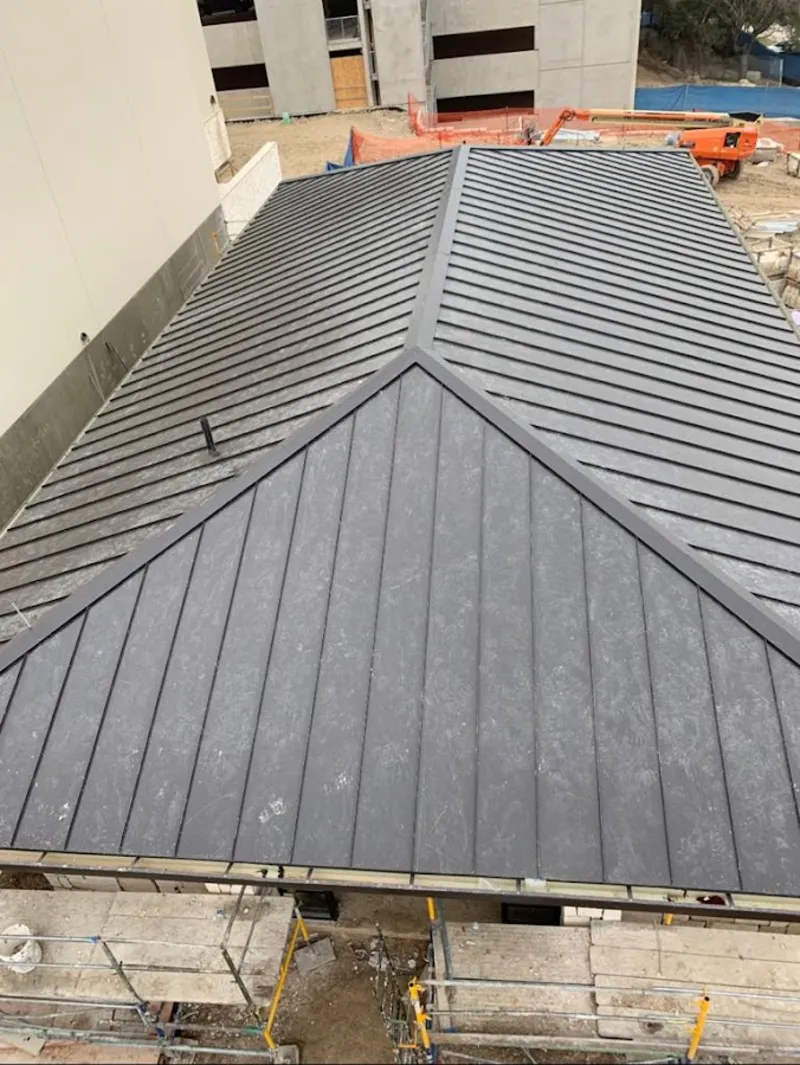 Commercial metal roof construction with crane equipment in Edinburg